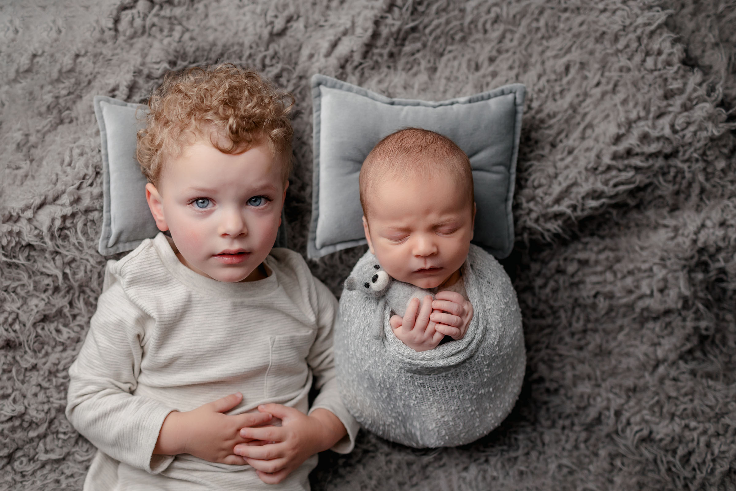 All gray setup with big brother and newborn brother for newborn photos in San Diego Photo Studio