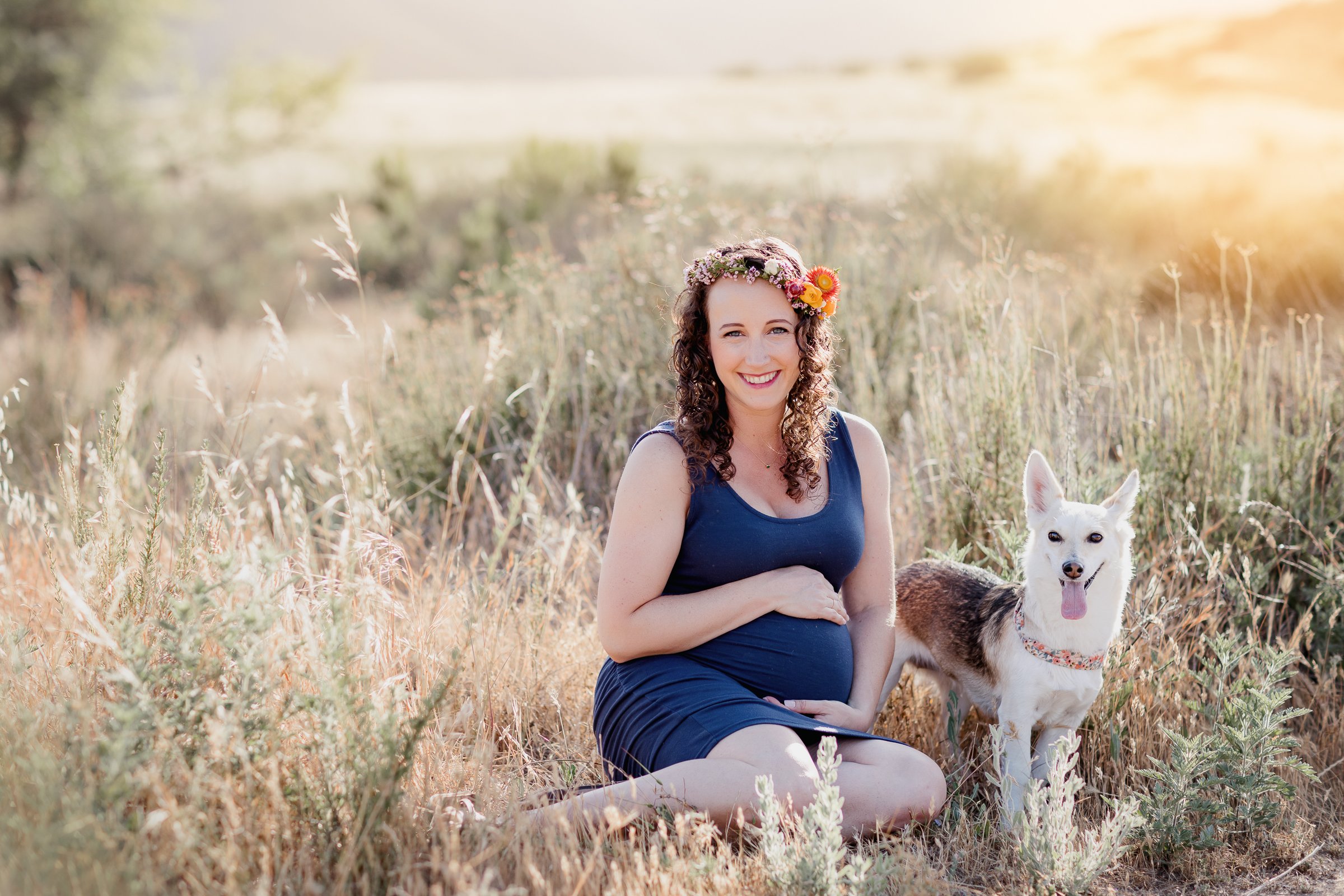 Image of pregnant mom during maternity photos outside at Mission Trails with dog sitting next to mom.