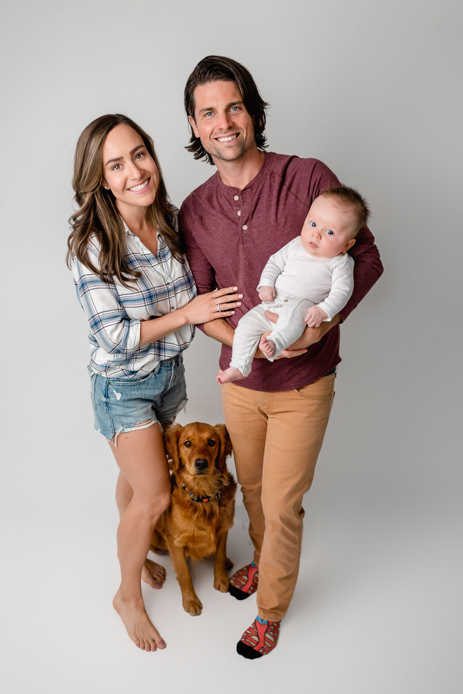 In Studio Family Photo on white backdrop with baby and golden retriever dog