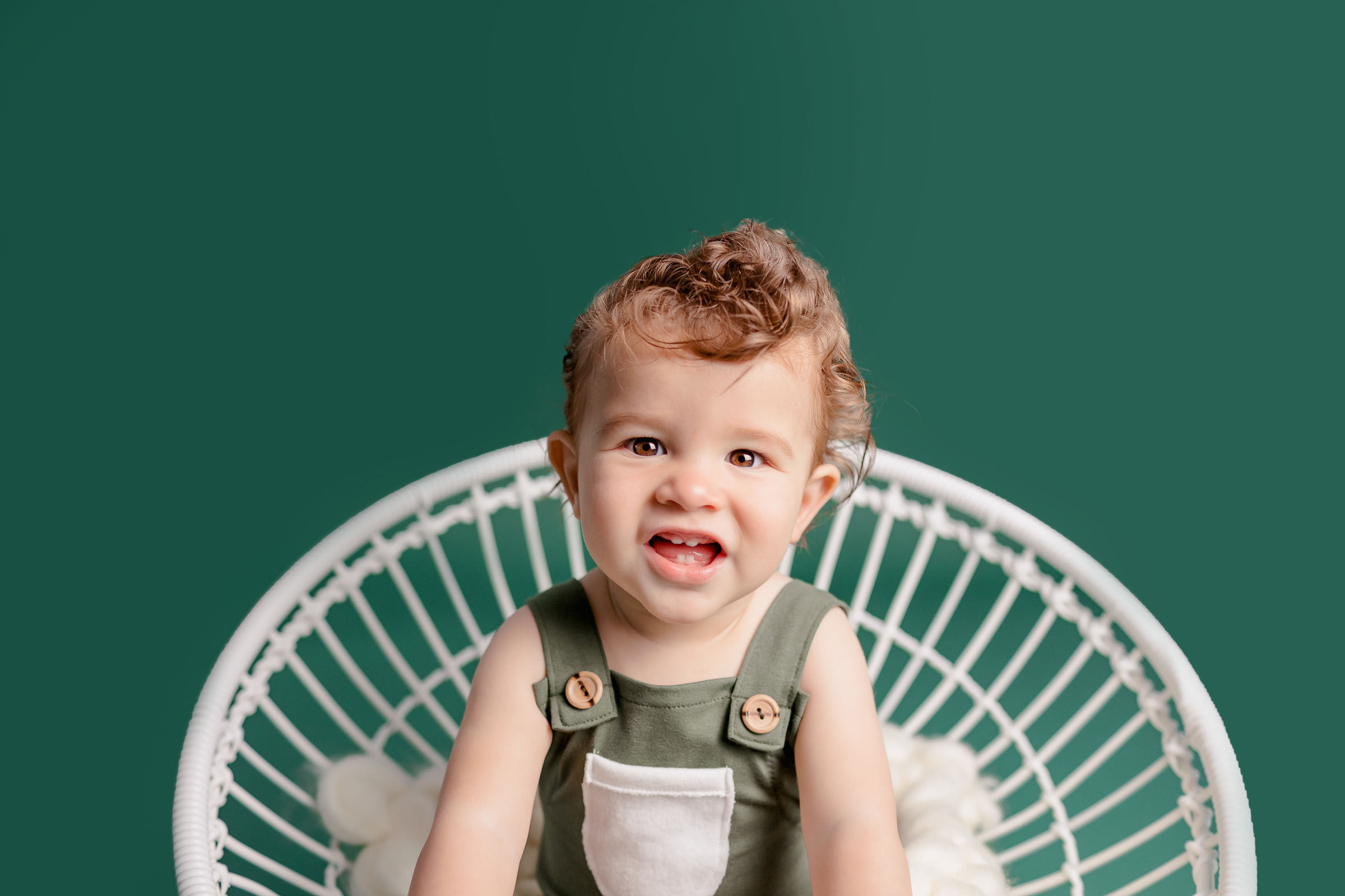 Toothy smile from a one year old dressed in green at San Diego Photo Studio