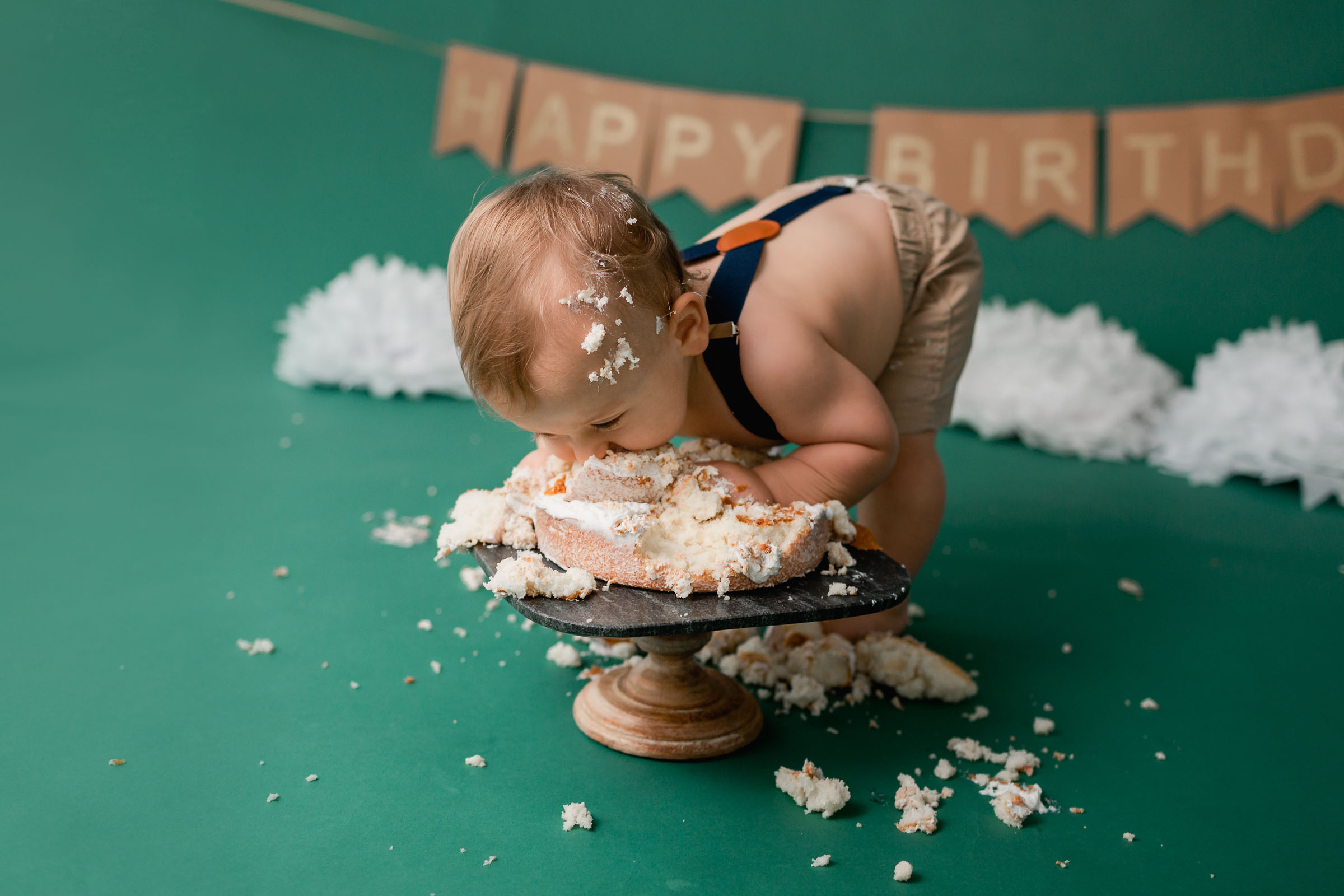 Face plant into a cake on green backdrop during a San Diego Cake Smash Session
