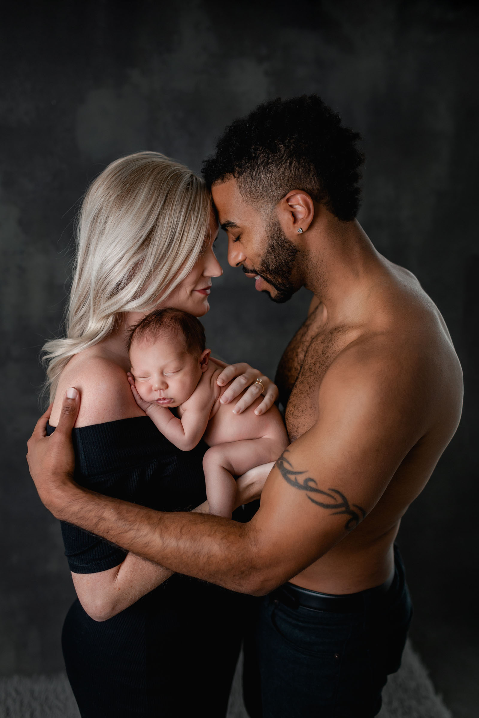 Close family pose of mom and dad during newborn photoshoot with baby between them
