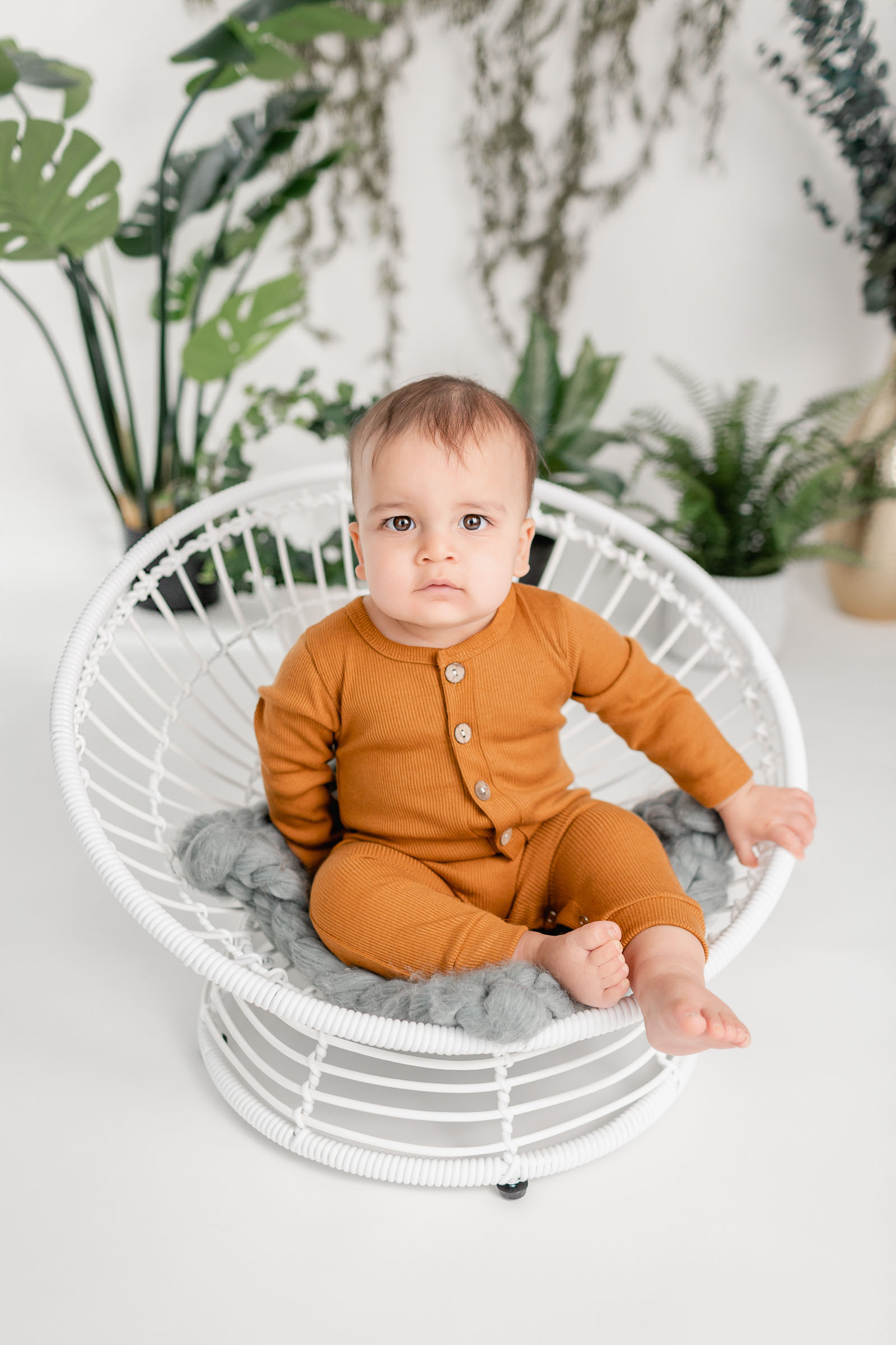 Baby boy dressed in an orange outfit on a white backdrop