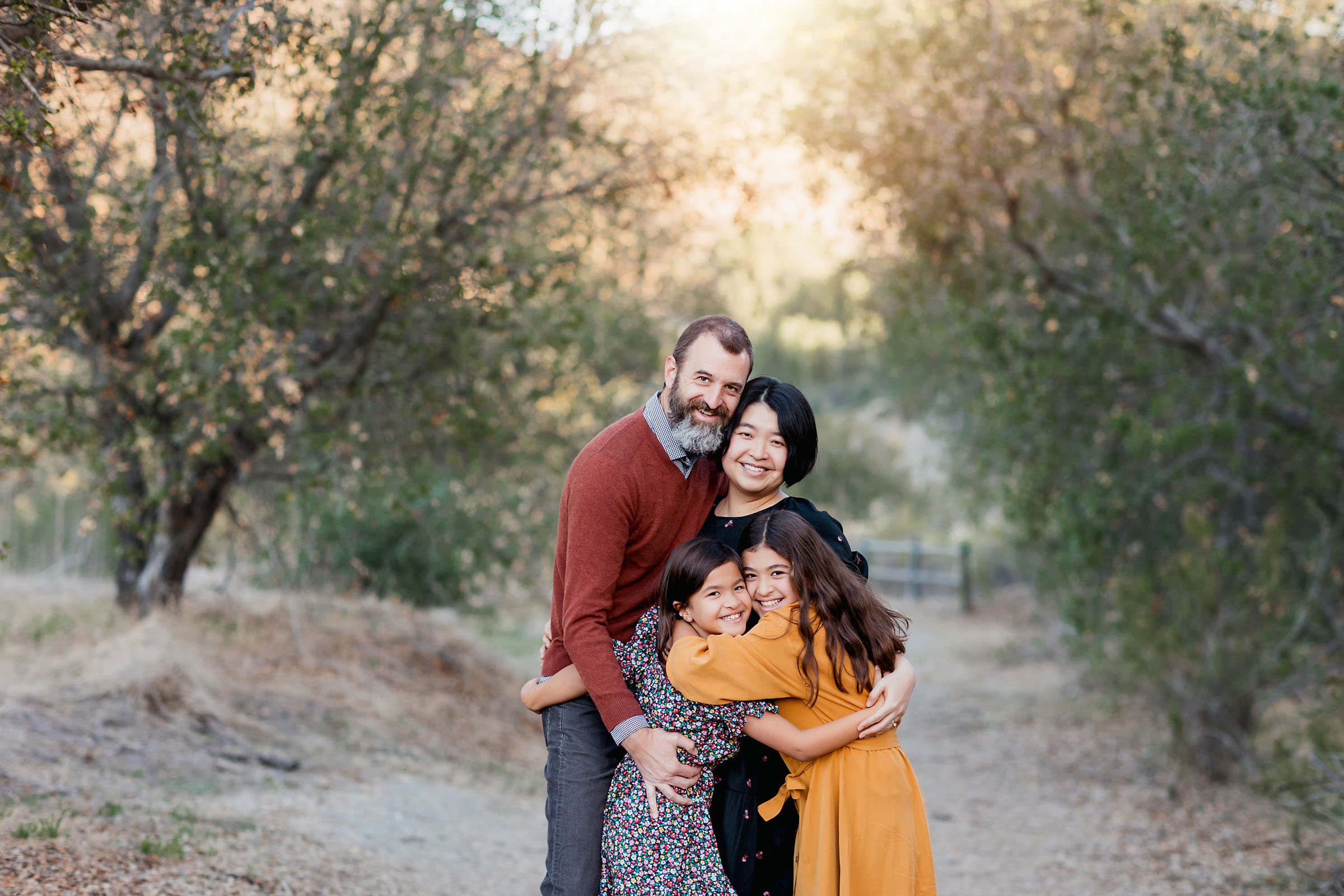 Mom and dad hugging their two daughters dressed in fall colors during family photos in San Diego