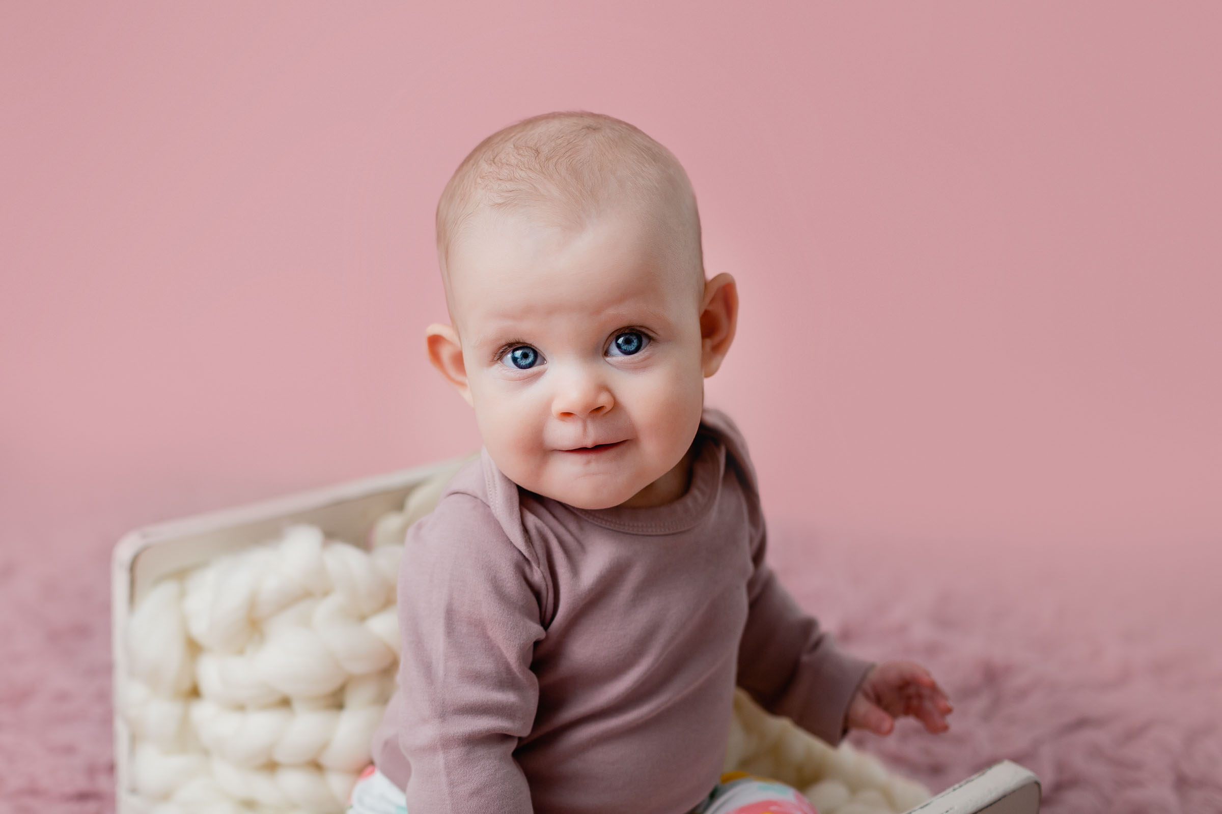 Close up of baby girl's face with pink accent tones for her milestone photoshoot