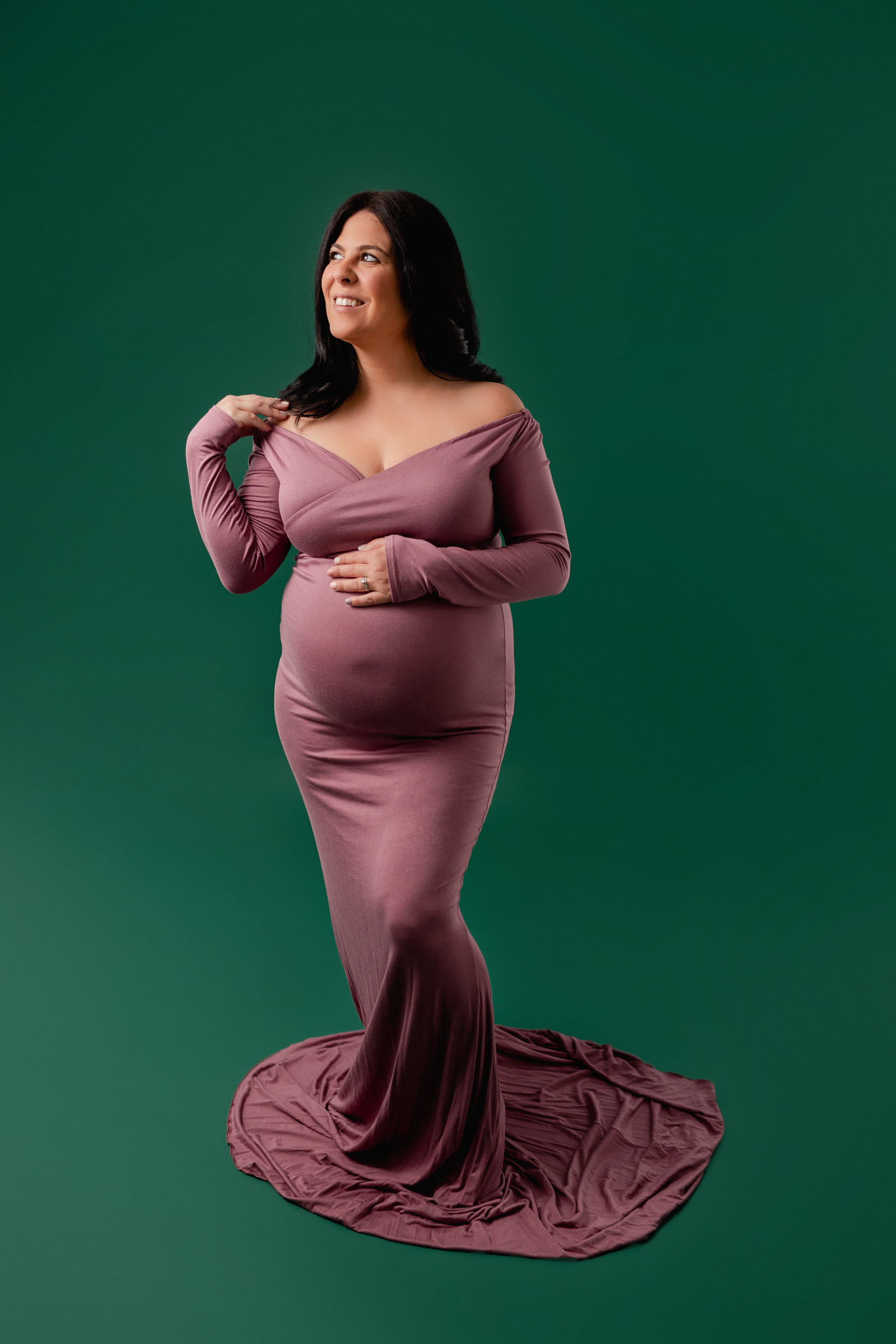 Pregnant mom in pink maternity dress on green backdrop