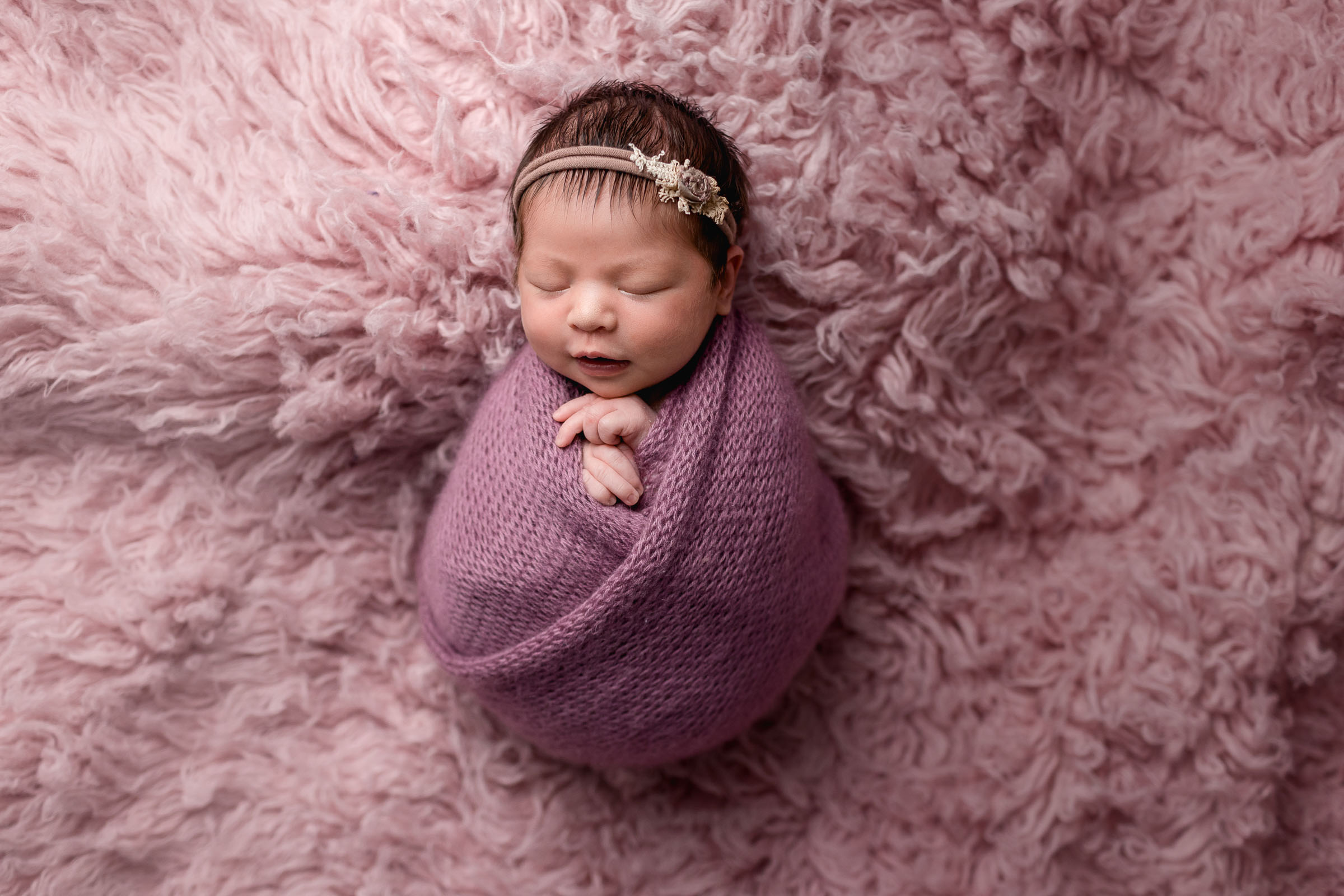 An all pink setup with newborn baby girl wrapped in pink