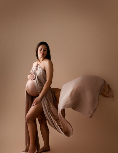 Pregnant mom captured by San Diego Maternity Photographer in Photo Studio with a drape flowing behind