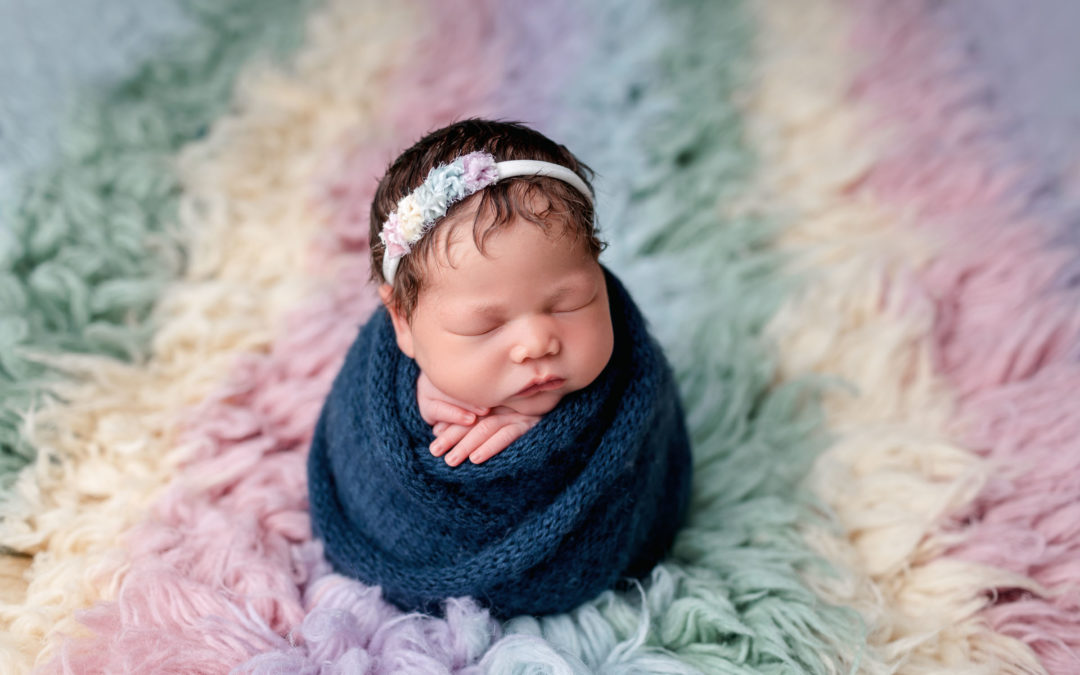 Colorful Studio Newborn Pictures in San Diego with baby on a rainbow flokati rug
