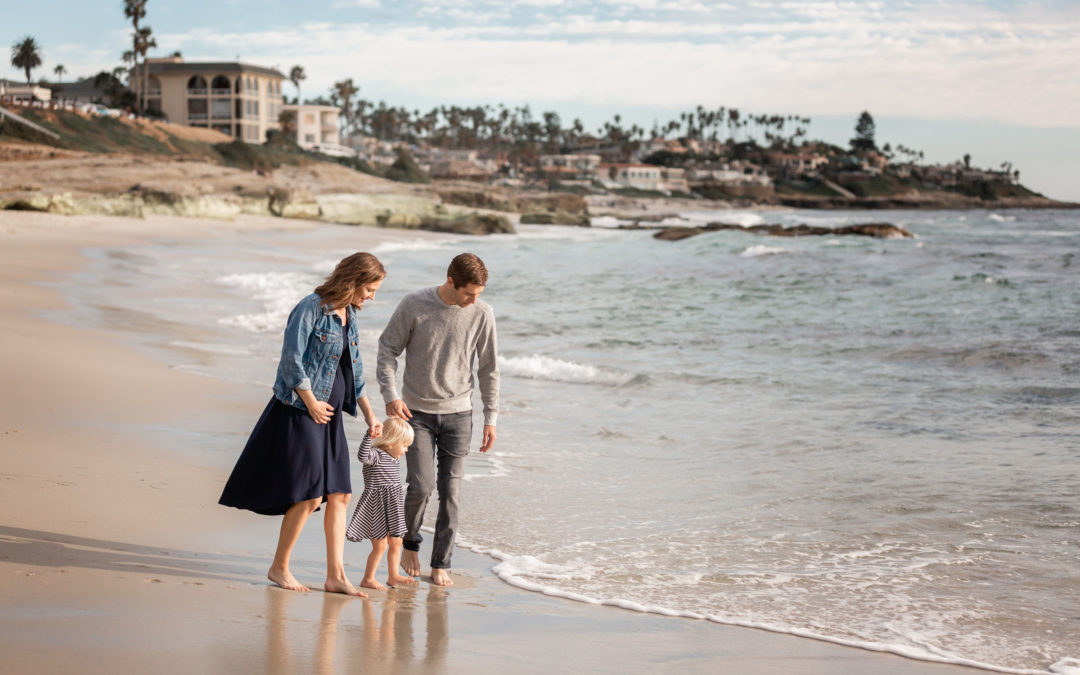 Best Locations for for San Diego Family Photos at Windansea Beach Pregnancy Announcement with family of three walking the beach hand in hand