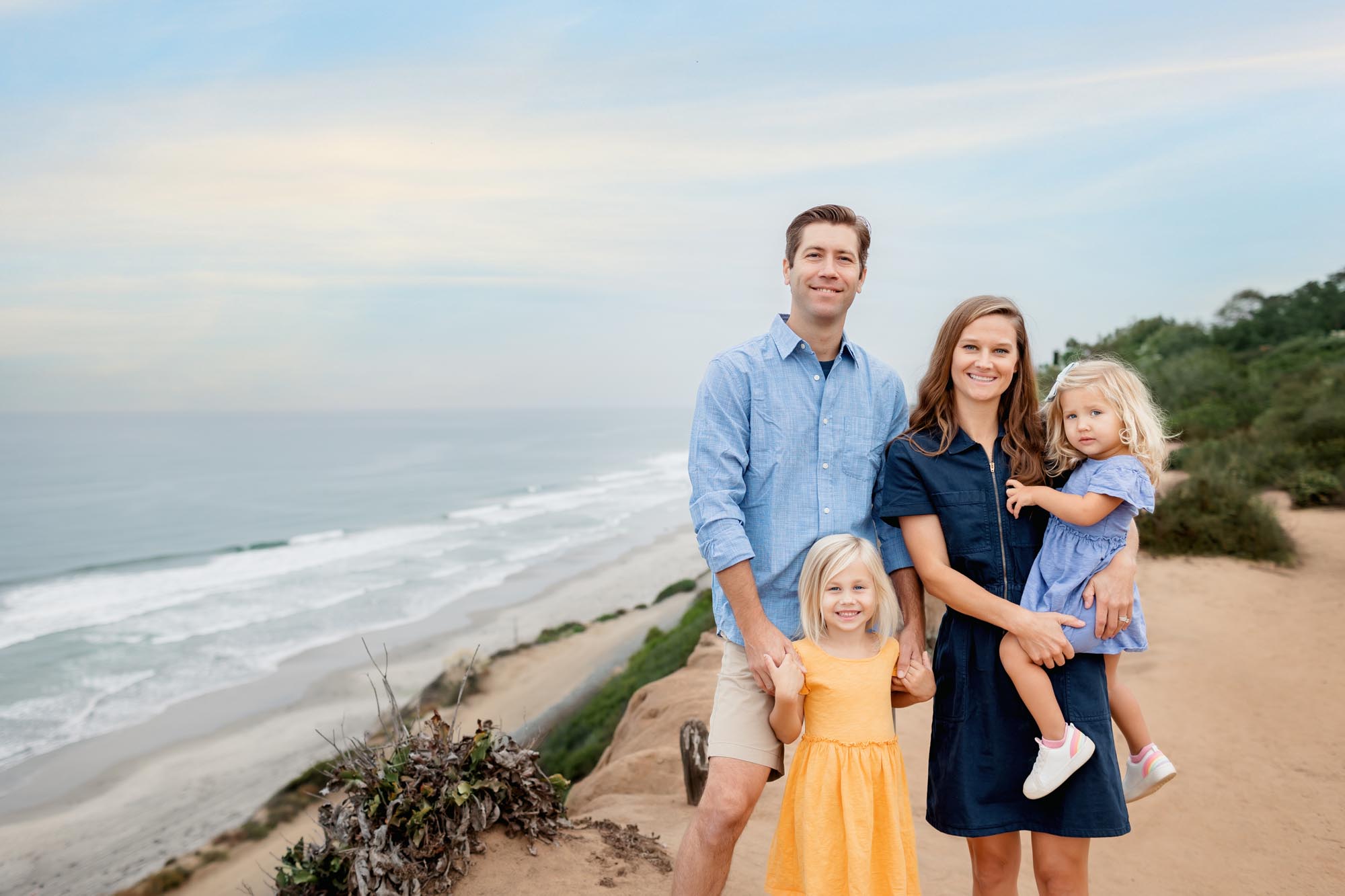 Family of four posing for family pictures at Torrey Pines with two little girls, mom and dad