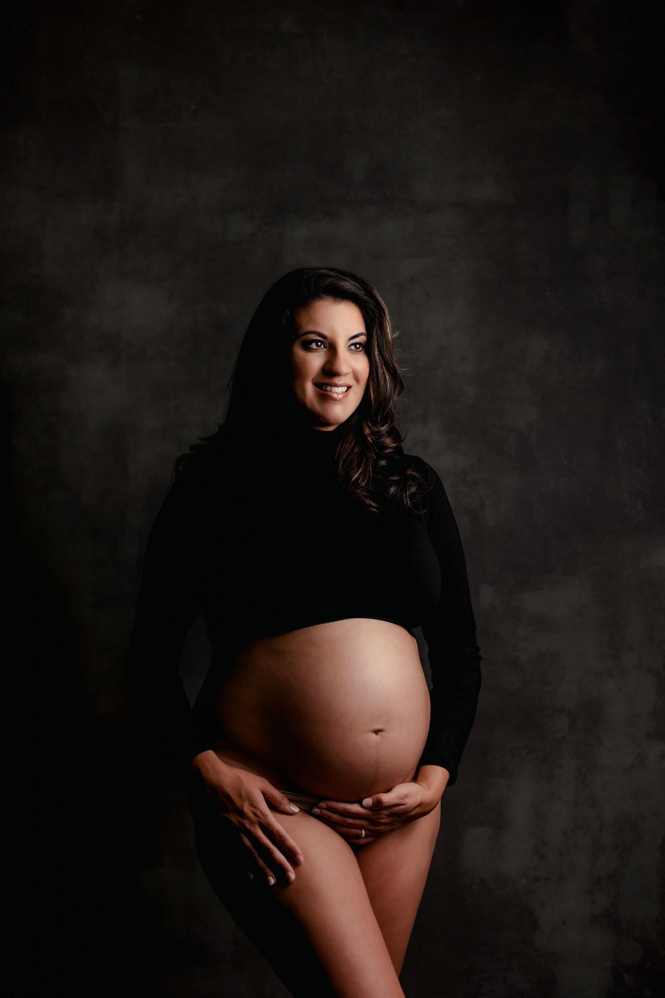 Fine Art Studio Maternity Picture of mom in black crop top with bare belly captured at a San Diego Professional Photography Studio