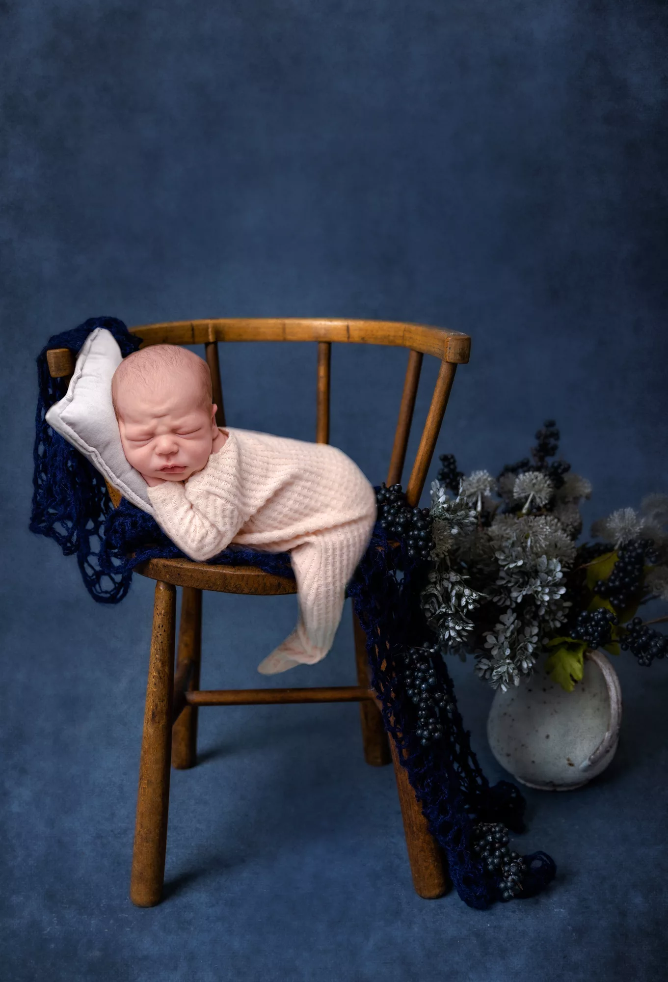 Newborn Boy Pictures on a chair with a blue backdrop