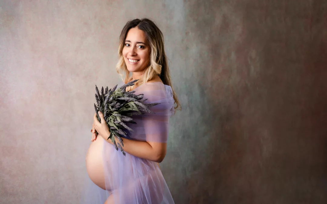 Lilac and Lavender inspired maternity shoot in studio of mom wearing a purple tulle fabric while holding lavender flowers shot by Maternity Photographer in San Diego