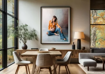 Scandinavian inspired dining room with wood accents and modern furniture featuring a large wall art maternity portrait of mom wearing an orange top and jeans with a bare belly sitting on the floor