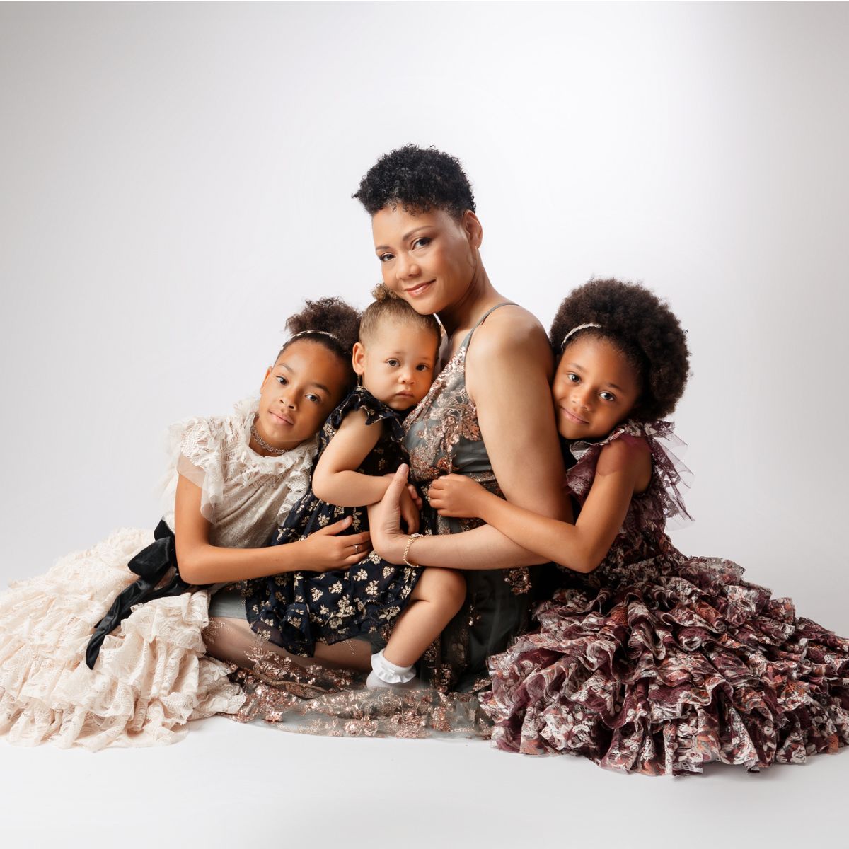 Stunning motherhood image of a mom surrounded by her three girls celebrating black mothers in a fine art studio portrait image