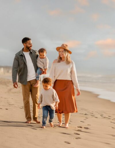 Family of four walking on the beach during family pictures in San Diego during sunset and golden glow