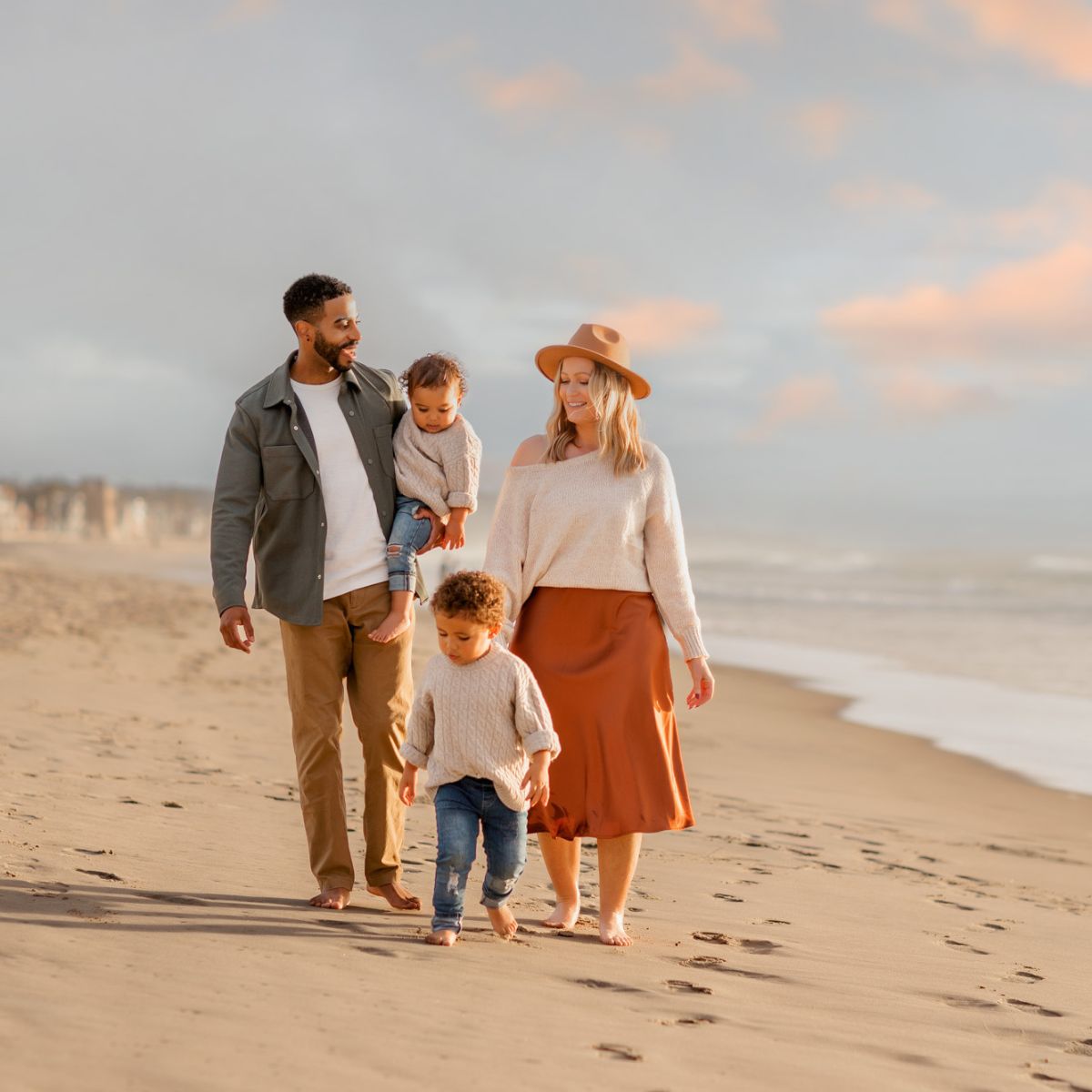 Family of four walking on the beach during family pictures in San Diego during sunset and golden glow