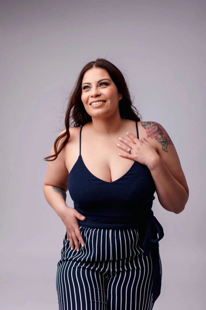 Corporate consultant walking confidently in a navy cami and striped pants, studio backdrop