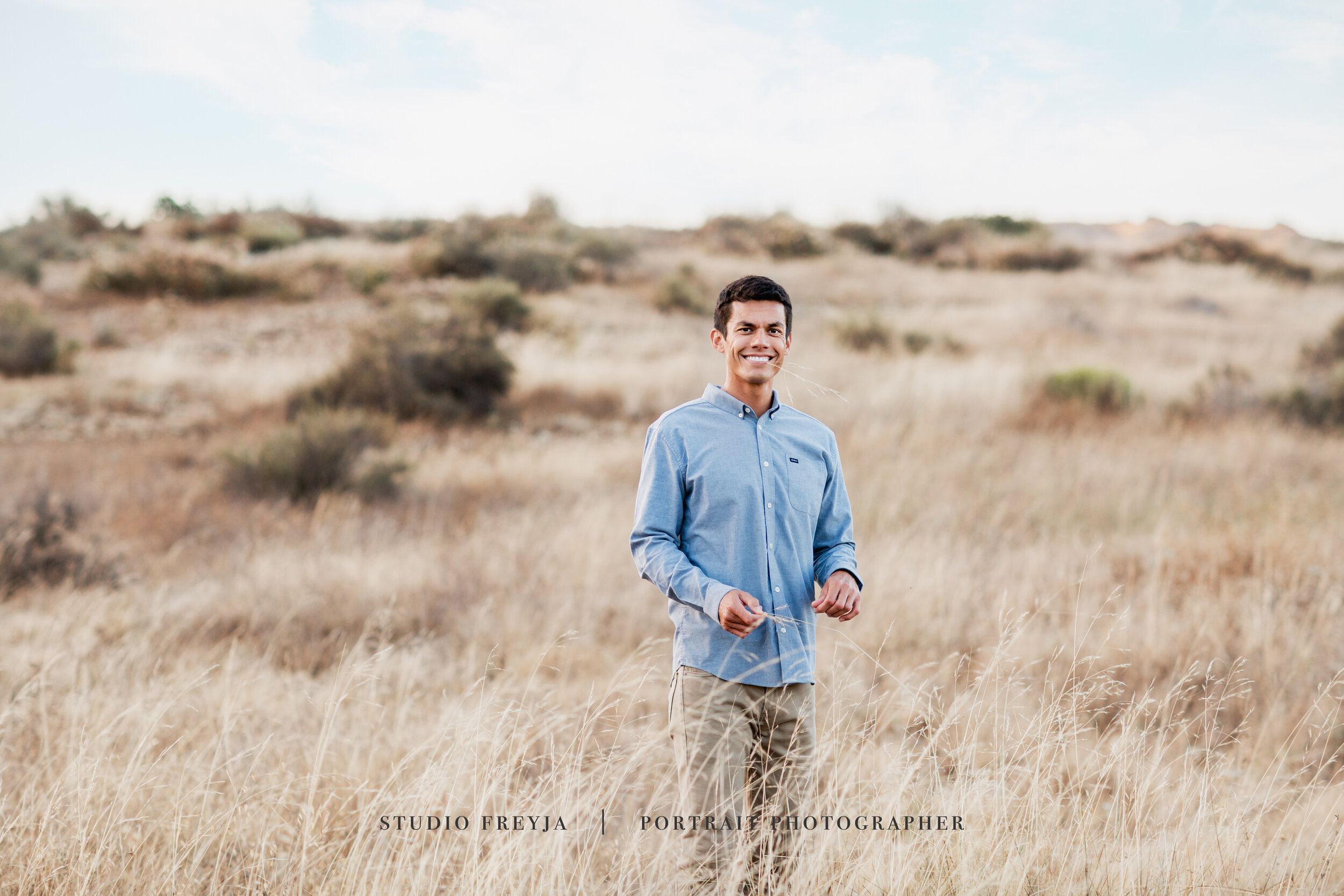 Smiling expectant father in a blue shirt standing in a golden field