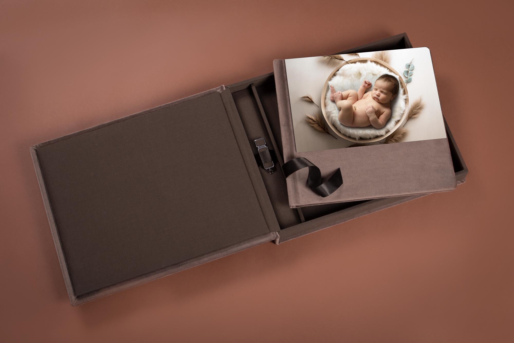 Brown linen folio box holding a newborn portrait print and a USB drive