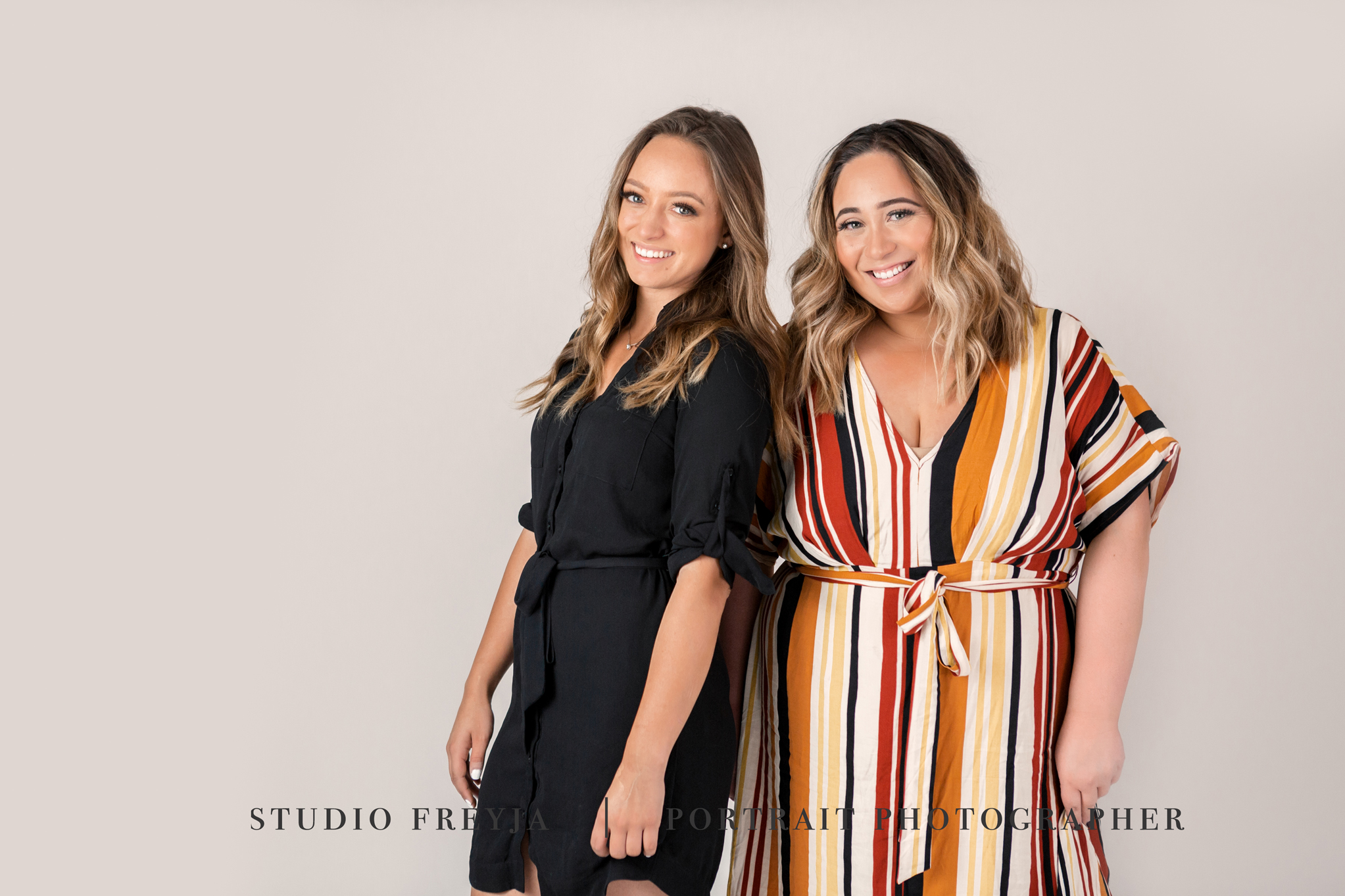 Two business partners standing side by side, one in black and one in a striped dress